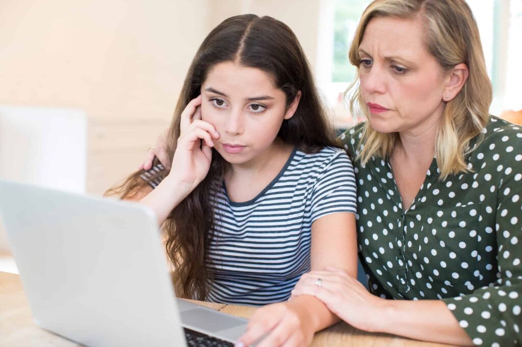 Mother sitting with daughter in front of laptop