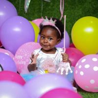 Young Black girl surrounded by colorful balloons