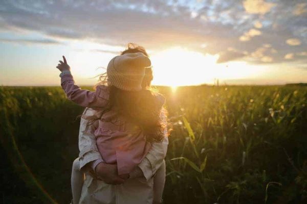 child with parent looking at sunset