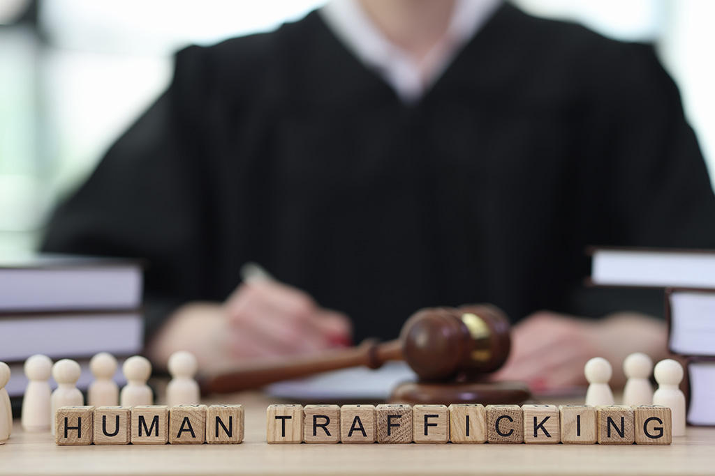 Phrase Human Trafficking with wooden cubes on judge counter in courtroom